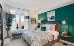 Redwood City, CA Apartments - Large Bedroom With Bed, Modern Decor, Window Seating, Nightstands With Lamps, Wall Decor, And A Green Accent Wall.