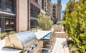 Apartments For Rent In Redwood City, CA - Rooftop BBQ Area With Grill, Dining Area, And Lush Landscaping.